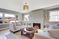 Light grey living rom with hardwood floor and rug. Furnished with white sofas and wooden coffee table